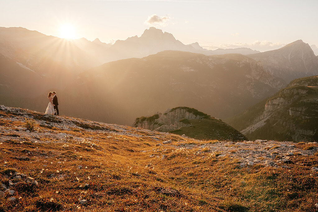 Couple embraces in mountain sunset landscape.