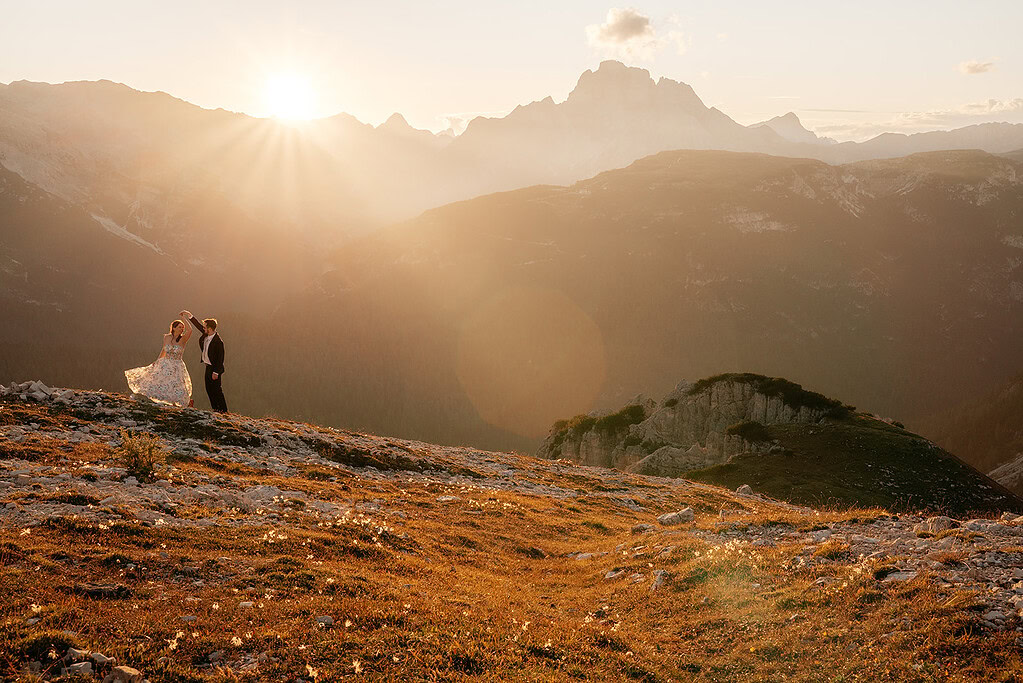Couple dancing on mountain at sunset.