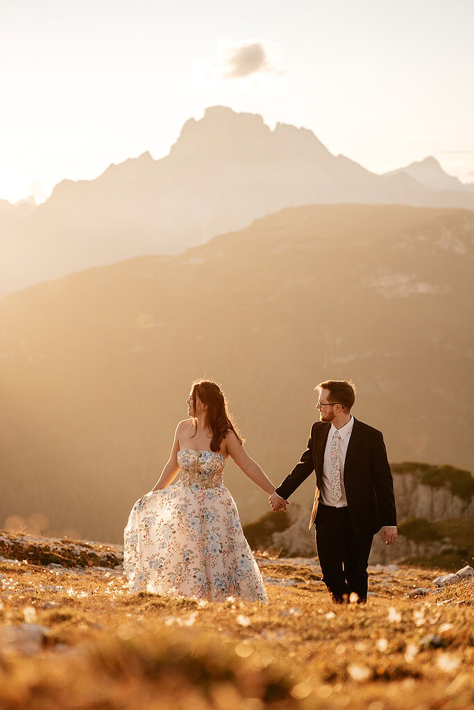 Couple holding hands at mountain sunset.