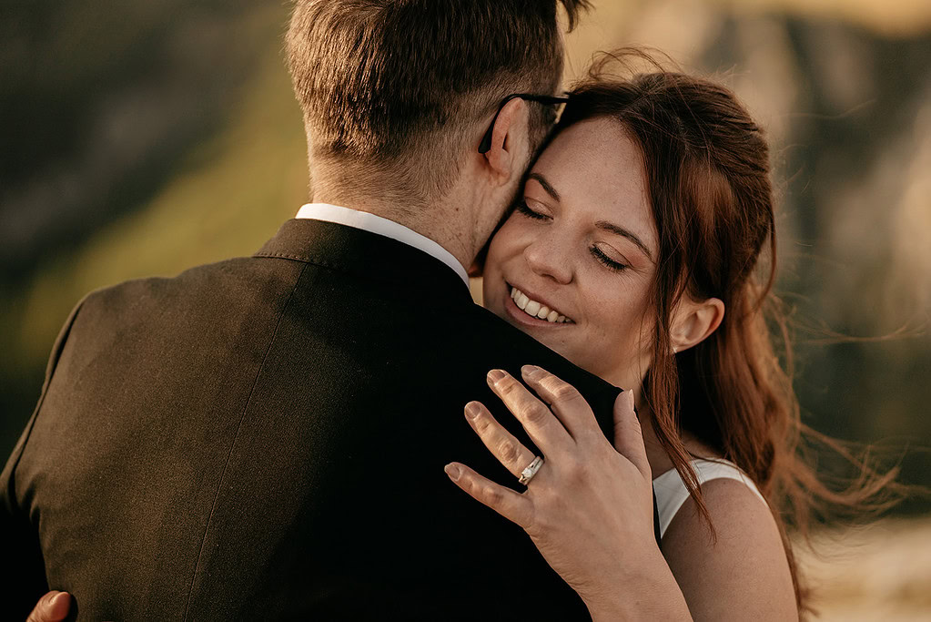 Couple hugging at sunset with smiles.