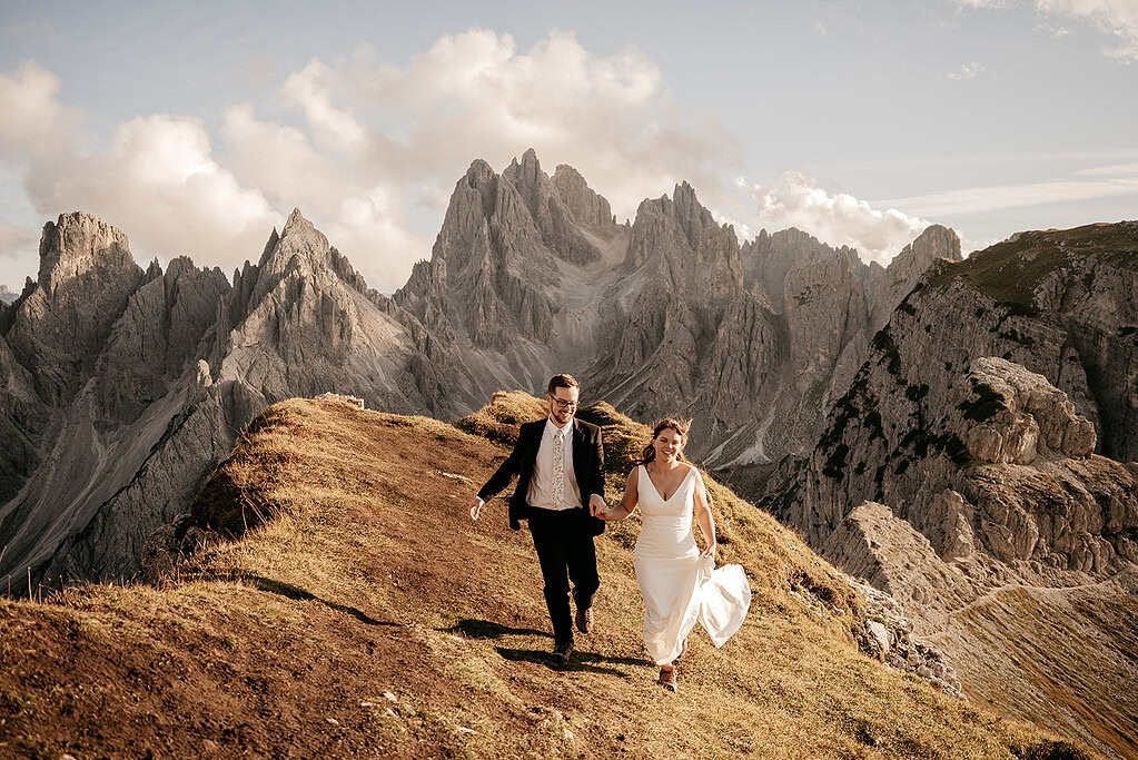 Bride and groom hiking in mountain landscape.