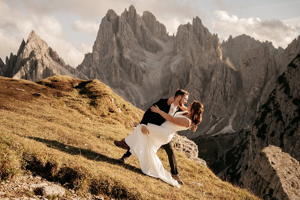 Couple dances on mountain with scenic backdrop.