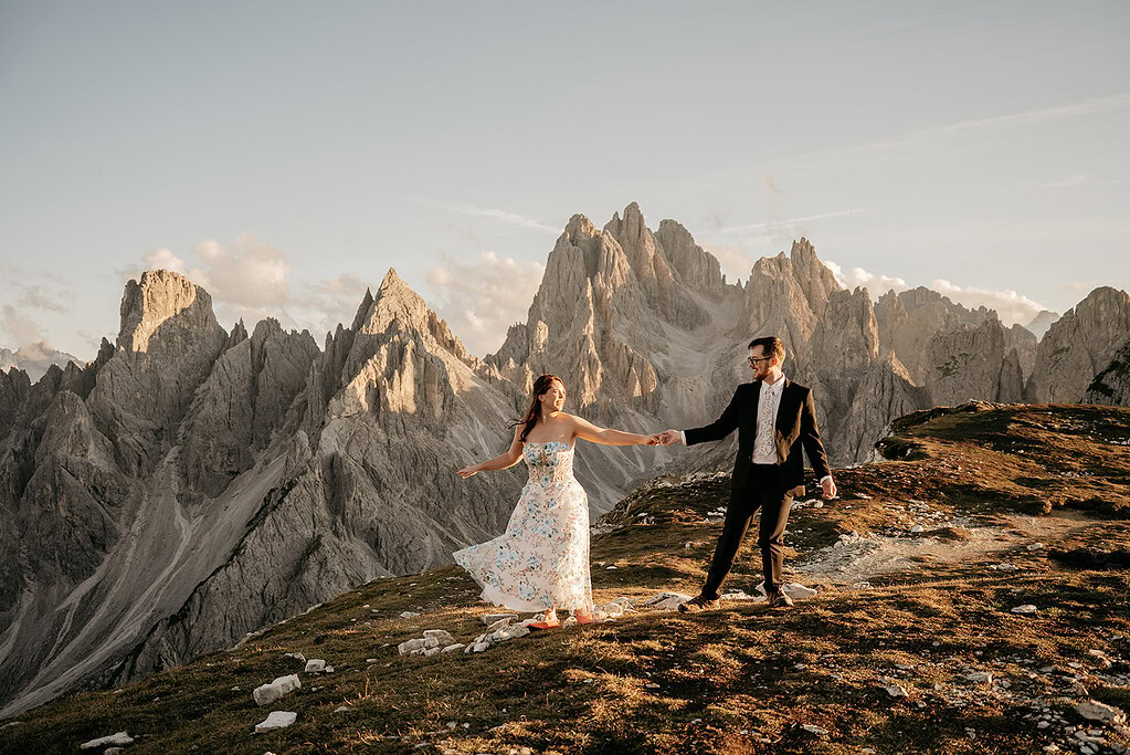 Couple holding hands on mountain landscape at sunset.