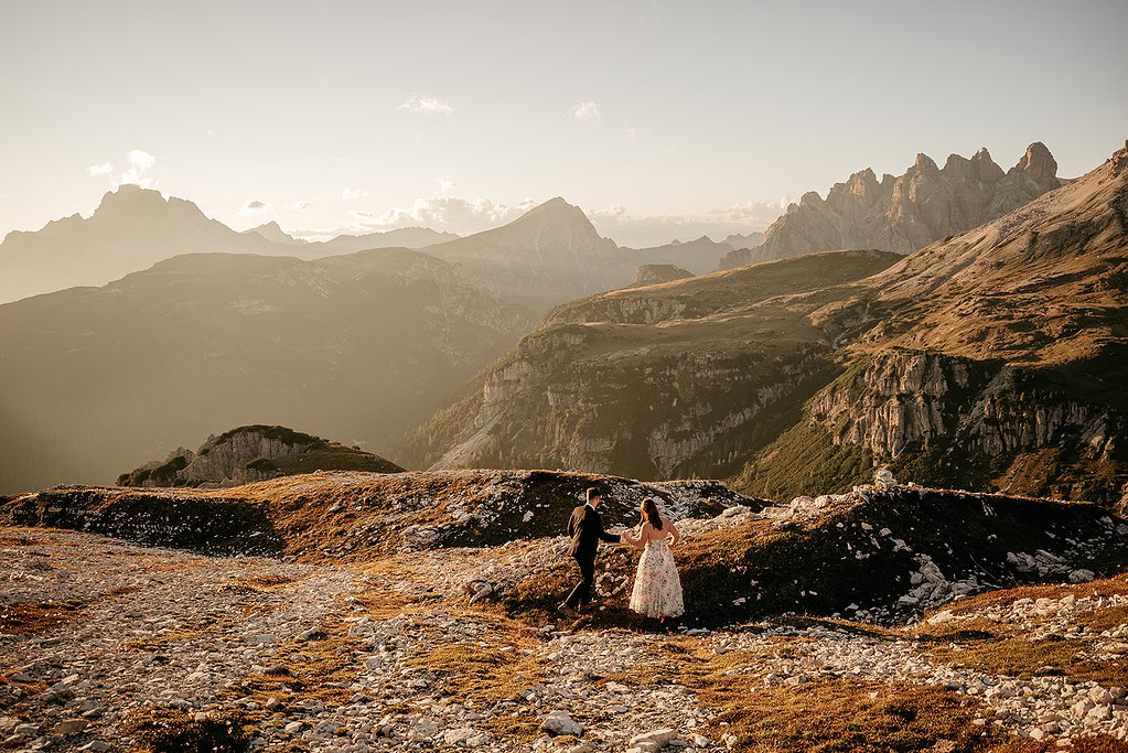 Couple walking in scenic mountain landscape at sunset.