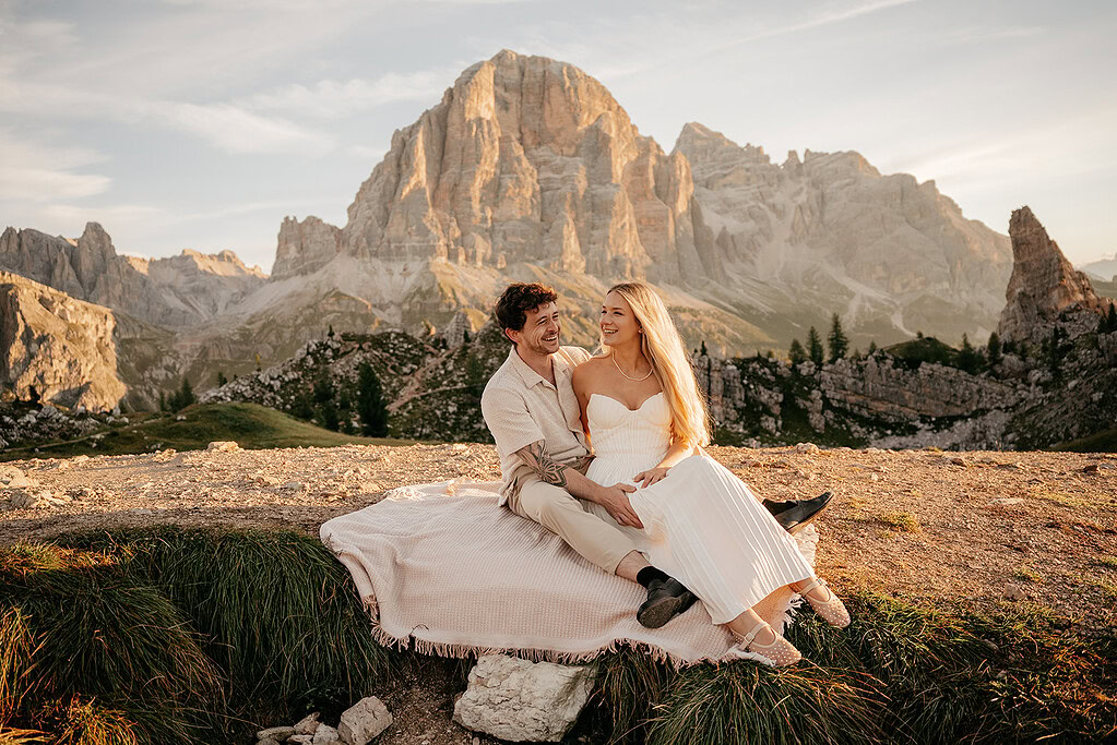 Couple smiling in front of mountain scenery at sunset.
