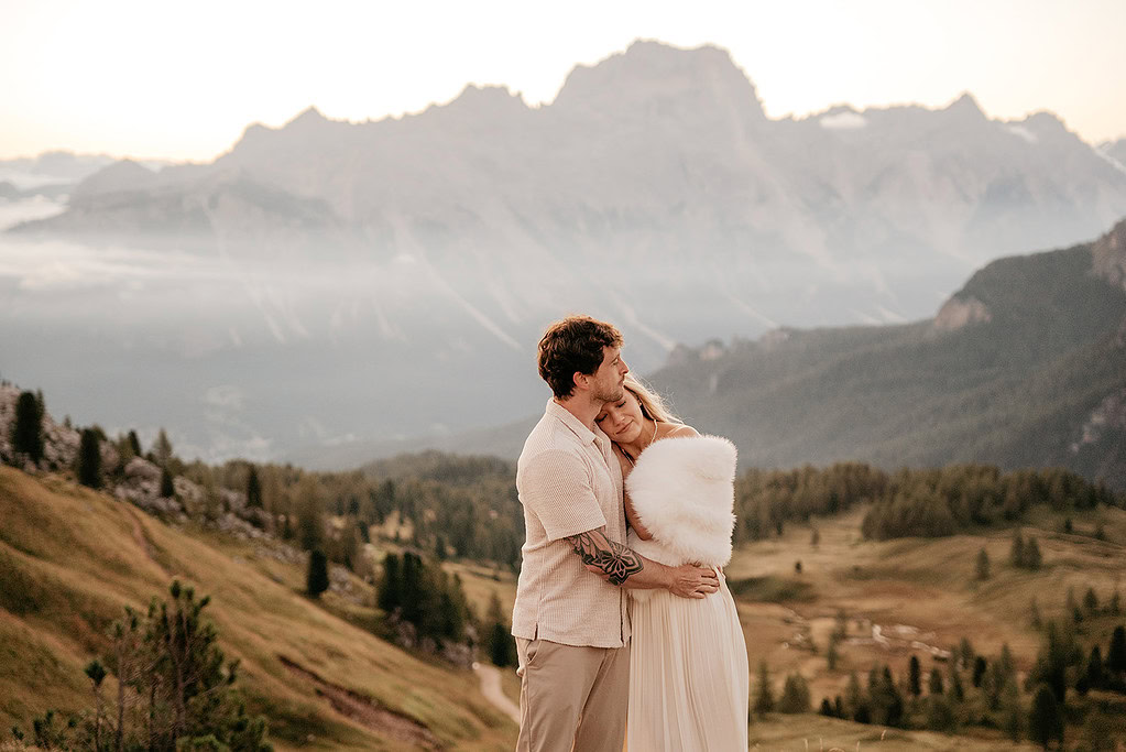 Couple hugging in scenic mountain landscape.