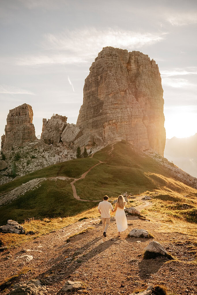 Couple walking toward towering mountain at sunset.
