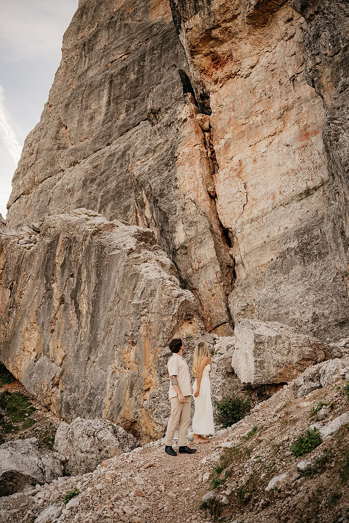 Couple standing by large rock face outdoors.