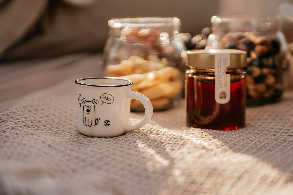 Mug with cartoon dog and snack jars on table.