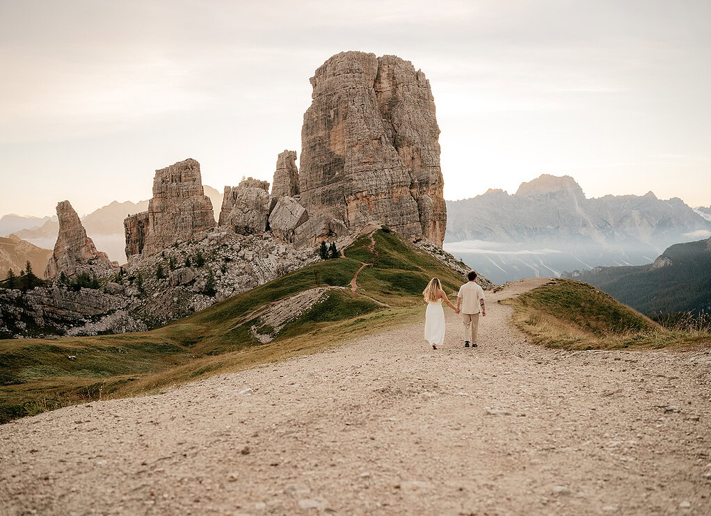 Couple walking on mountain path at sunset.