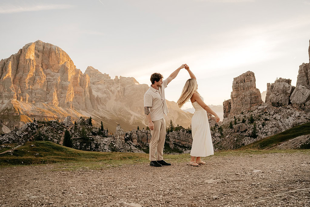 Couple dancing in scenic mountain landscape at sunset.