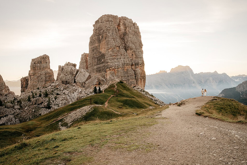 Couple walking on mountain path at sunset.