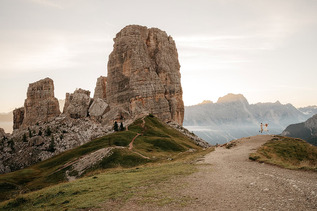 Couple hiking near dramatic mountain landscape at sunrise.