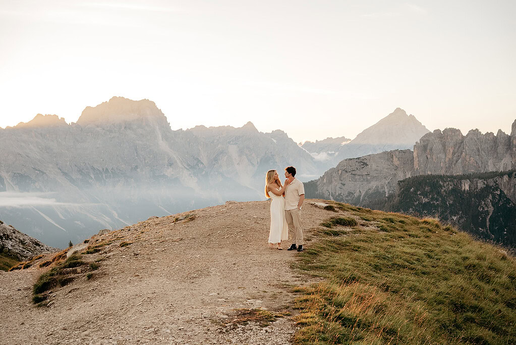 Couple standing on mountain at sunset view.