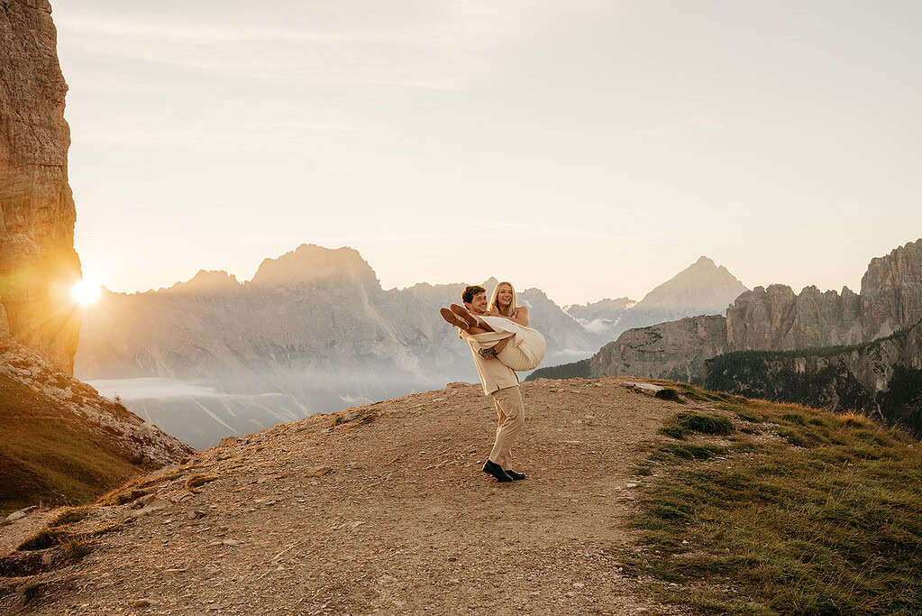 Couple celebrating wedding on mountain at sunrise.
