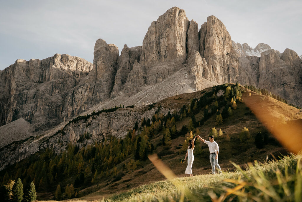 Couple dancing in front of dramatic mountain landscape.