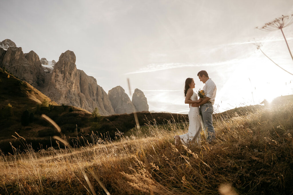 Couple embraces in mountain landscape at sunset.