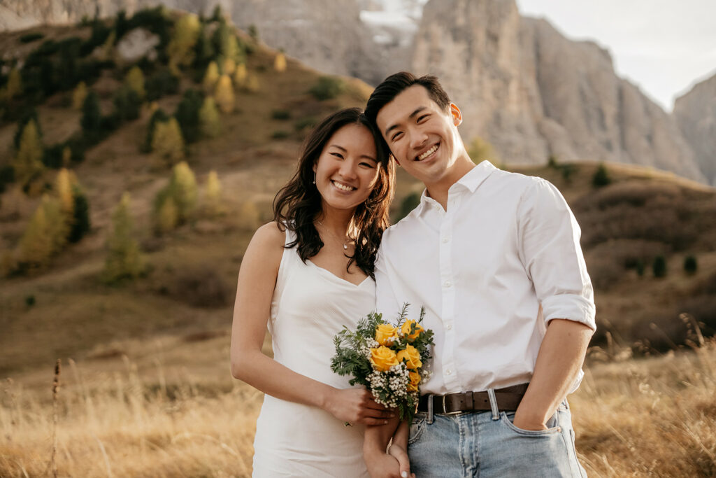 Couple smiling in scenic mountain landscape.