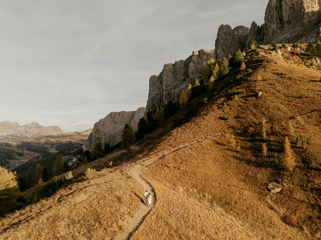 Hikers on scenic mountain trail with rocky landscape.