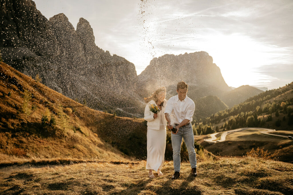 Couple celebrating with champagne in mountain landscape.