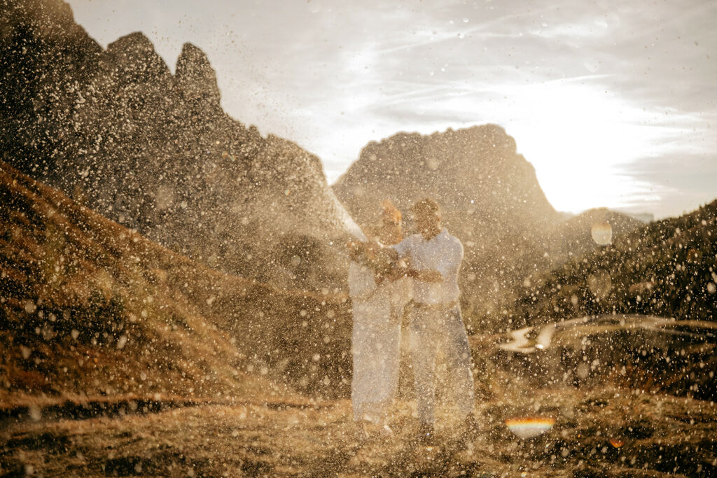Couple celebrating with champagne in scenic mountains.