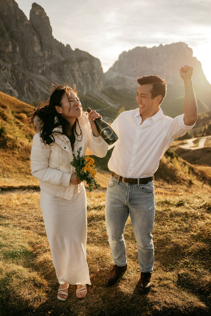 Couple celebrating with champagne in scenic landscape.