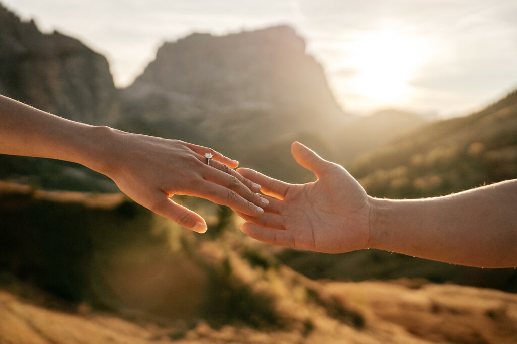 Engagement ring on hand in scenic sunset background