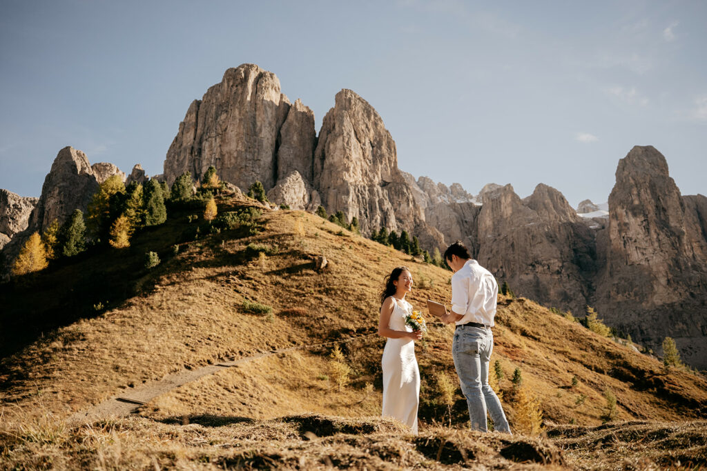 Couple exchanging vows on scenic mountain landscape.