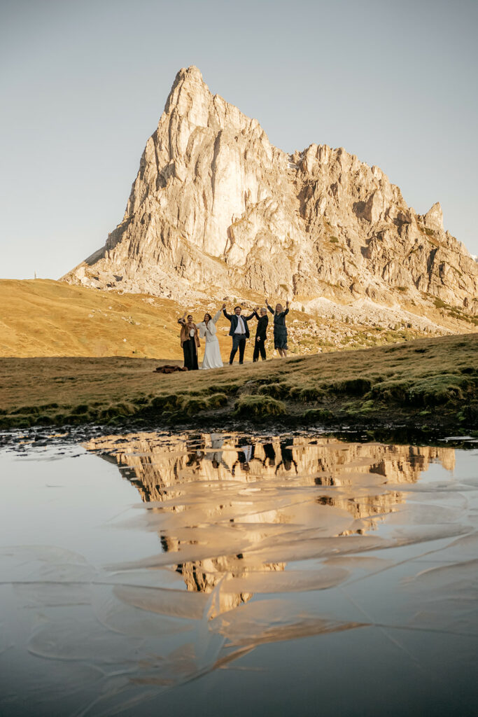 Group celebrating by mountain and lake reflection