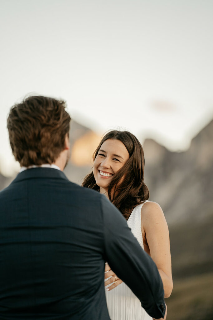 Smiling couple outdoors with mountains backdrop.