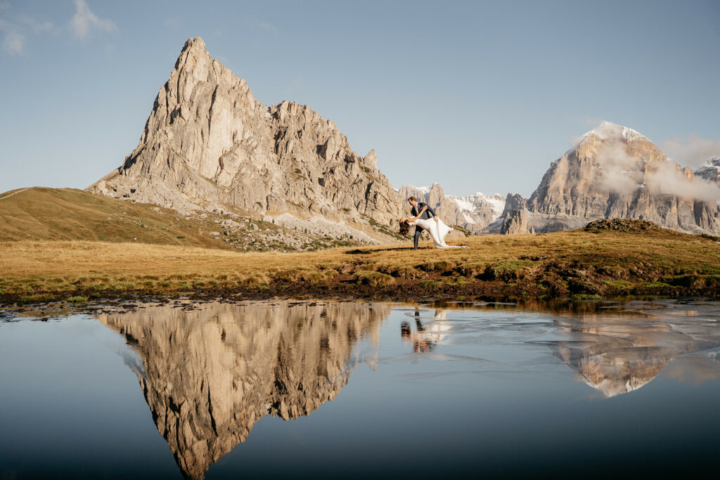 Couple dances by mountain reflection in lake