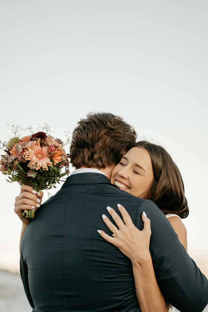 Couple hugging, holding a flower bouquet.