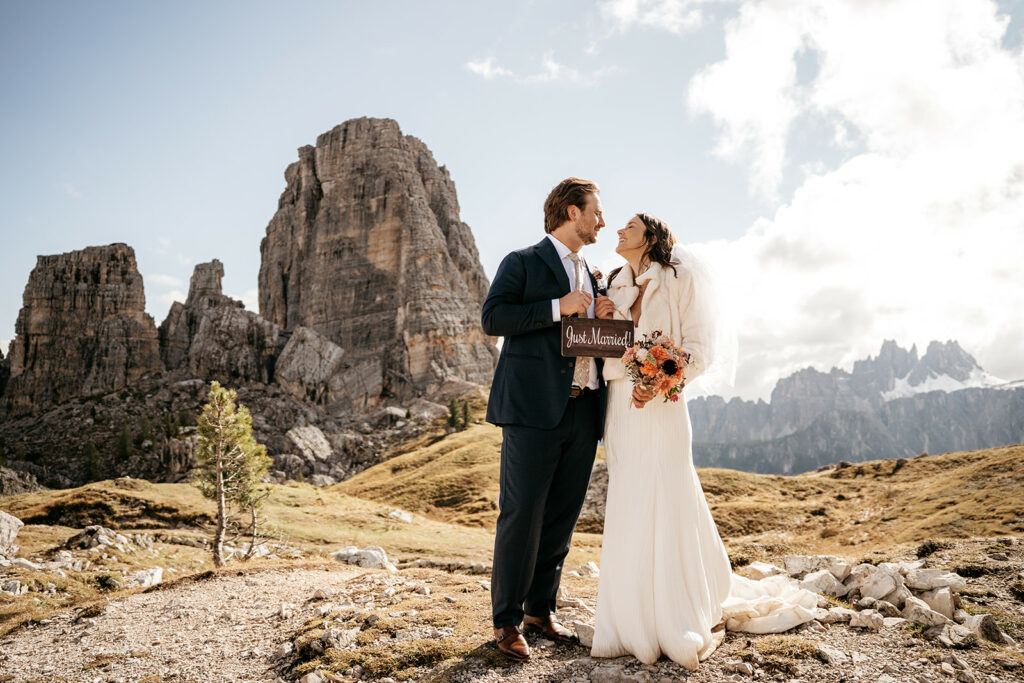 Couple holding 'Just Married' sign, mountain background.