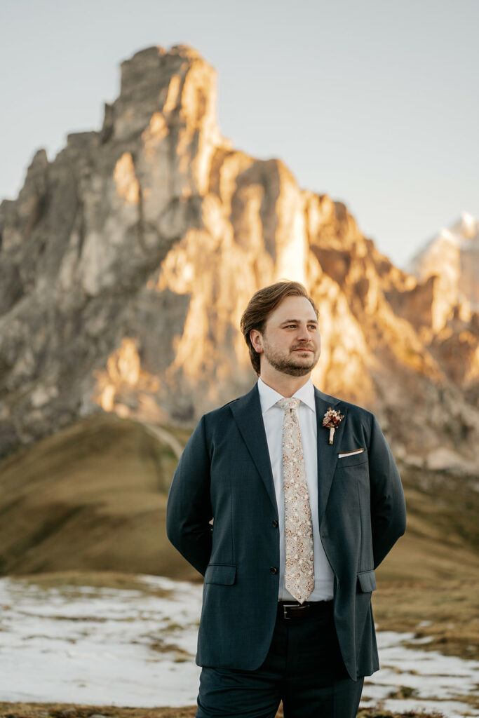 Man in suit at mountain landscape during sunset.