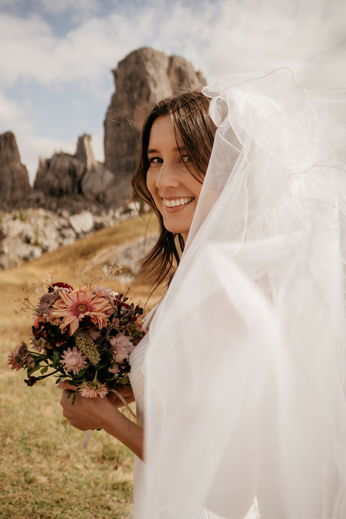 Bride smiling with bouquet and veil outdoors