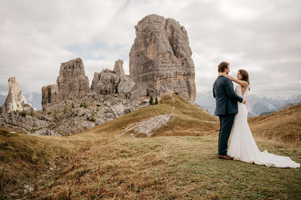 Bride and groom embrace in mountain landscape