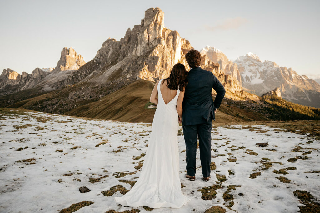 Couple admiring snowy mountain landscape at sunset.