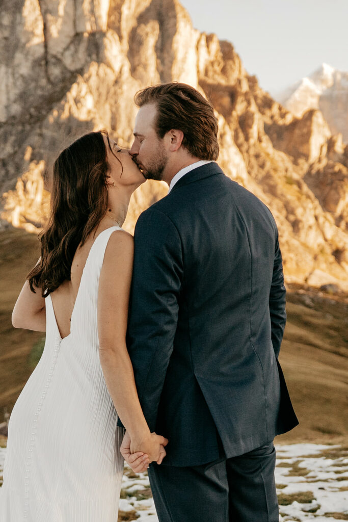 Couple kissing in mountainous landscape.