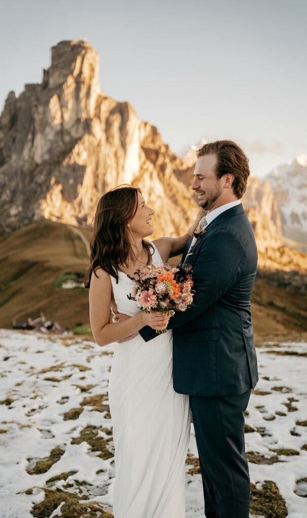 Smiling couple in wedding attire on snowy mountain