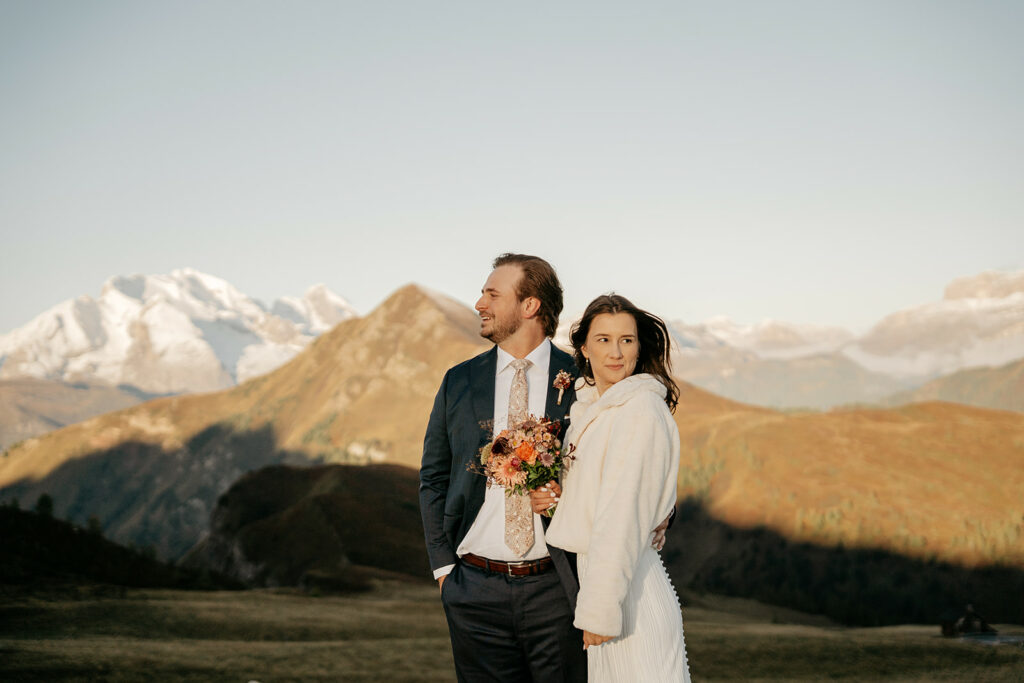 Couple in wedding attire with mountain backdrop.