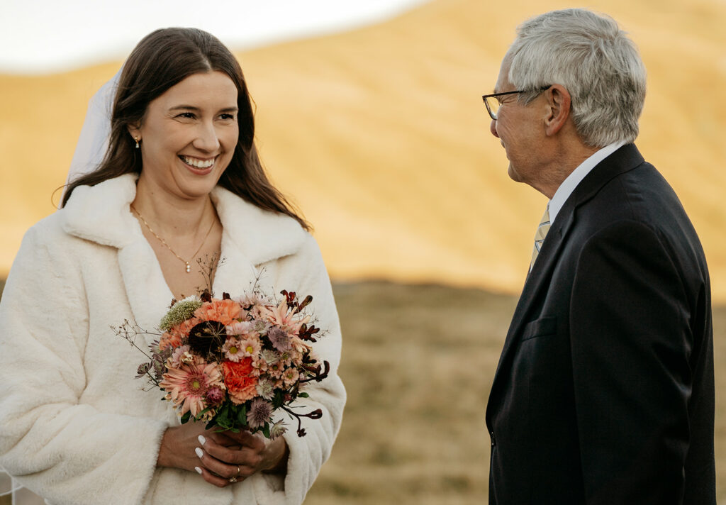 Bride smiling, holding a bouquet, outdoors wedding