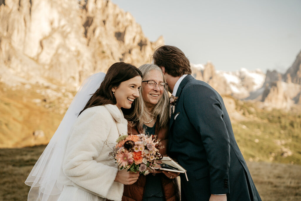 Wedding couple hugging woman in scenic mountains