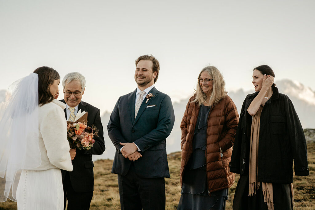 Outdoor wedding ceremony with officiant and guests smiling.