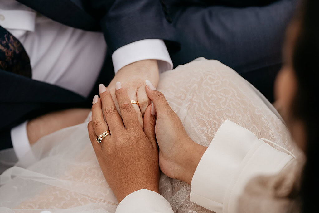 Couple holding hands, wedding rings visible
