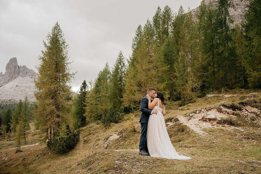 Couple embracing in scenic mountainous forest landscape.