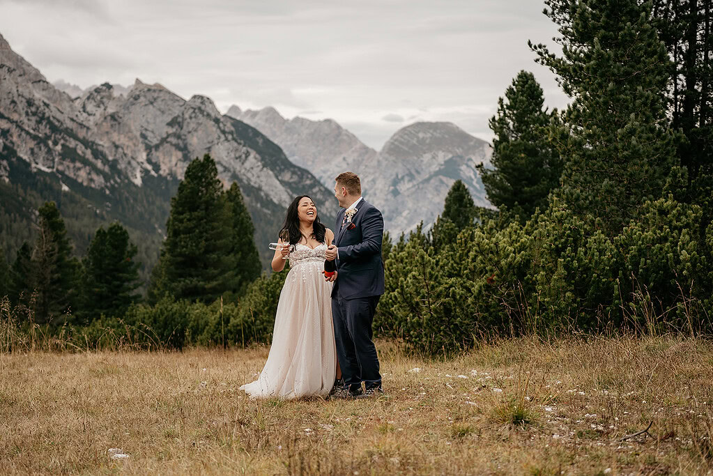 Couple celebrating with champagne in mountain landscape.