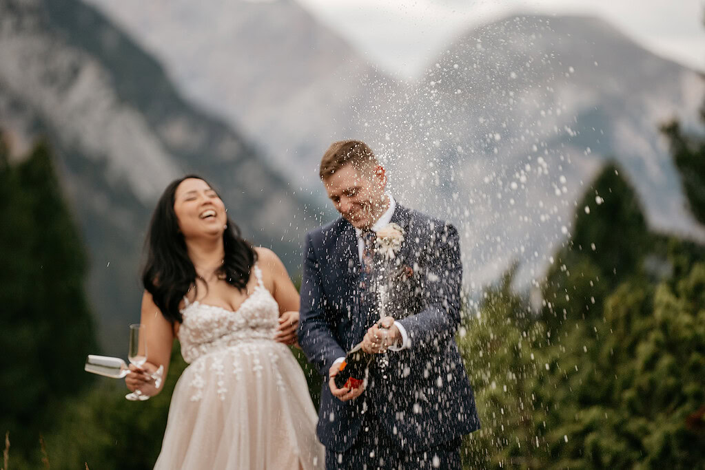 Couple celebrating with champagne, mountains in background