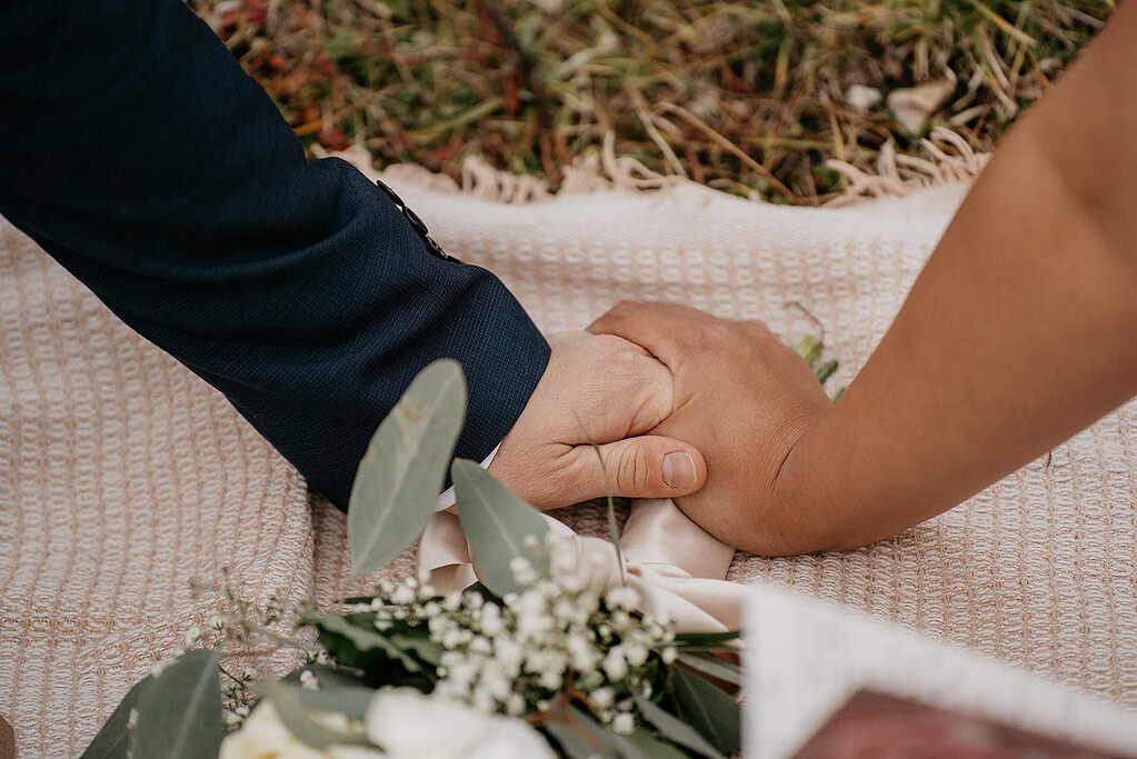 Couple holding hands at an outdoor ceremony