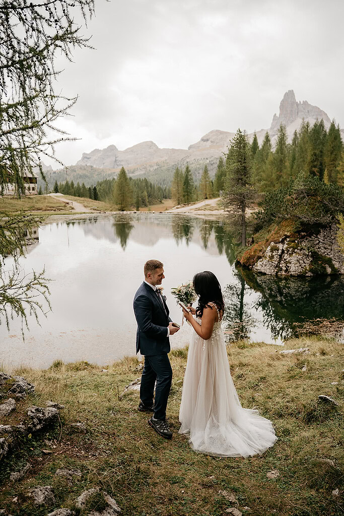 Couple exchanging vows by mountain lake.