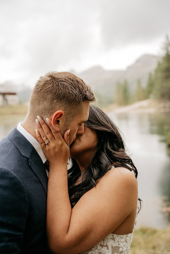 Couple kissing by a mountain lake.
